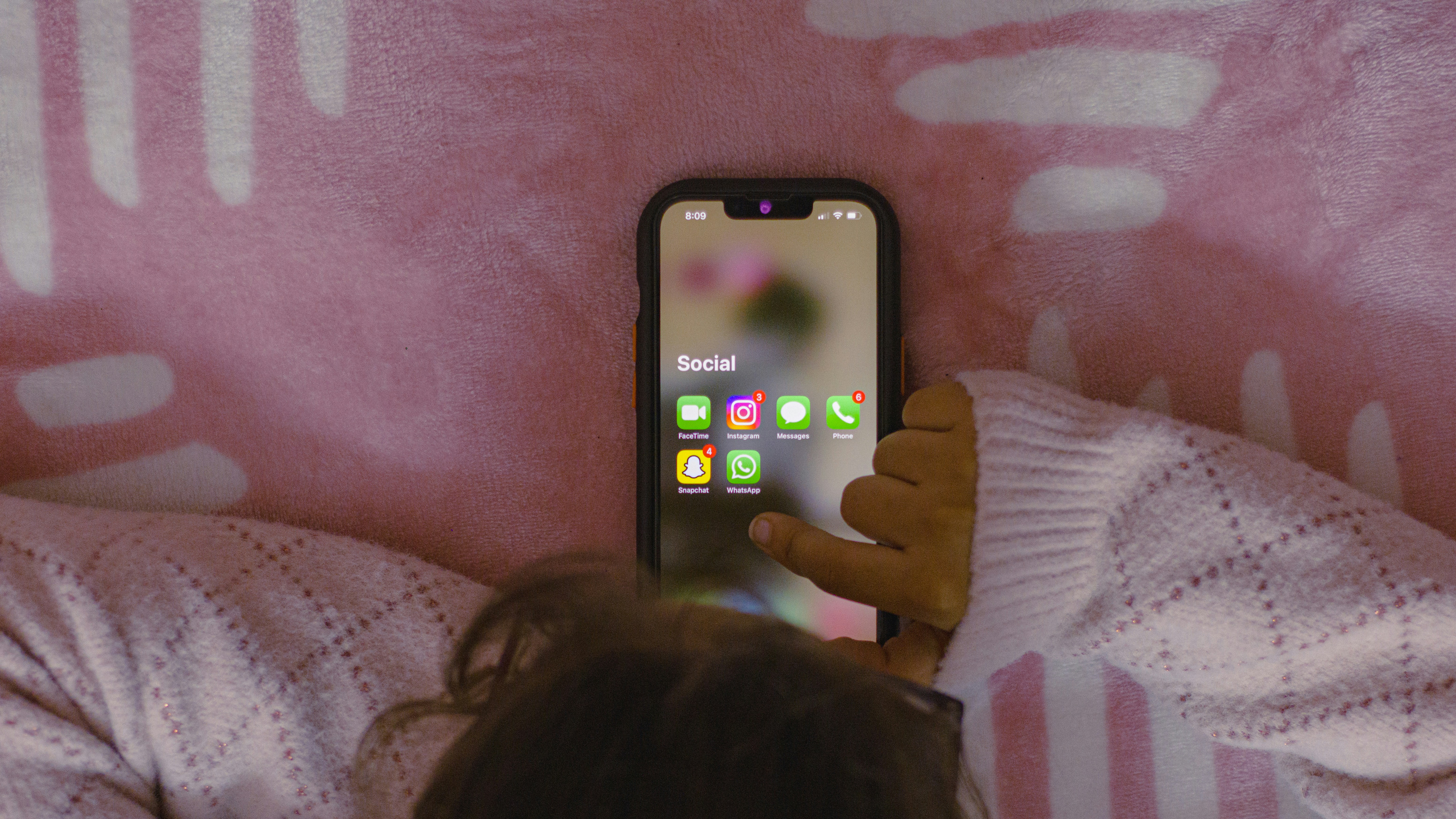 Child browsing social apps on phone in bed